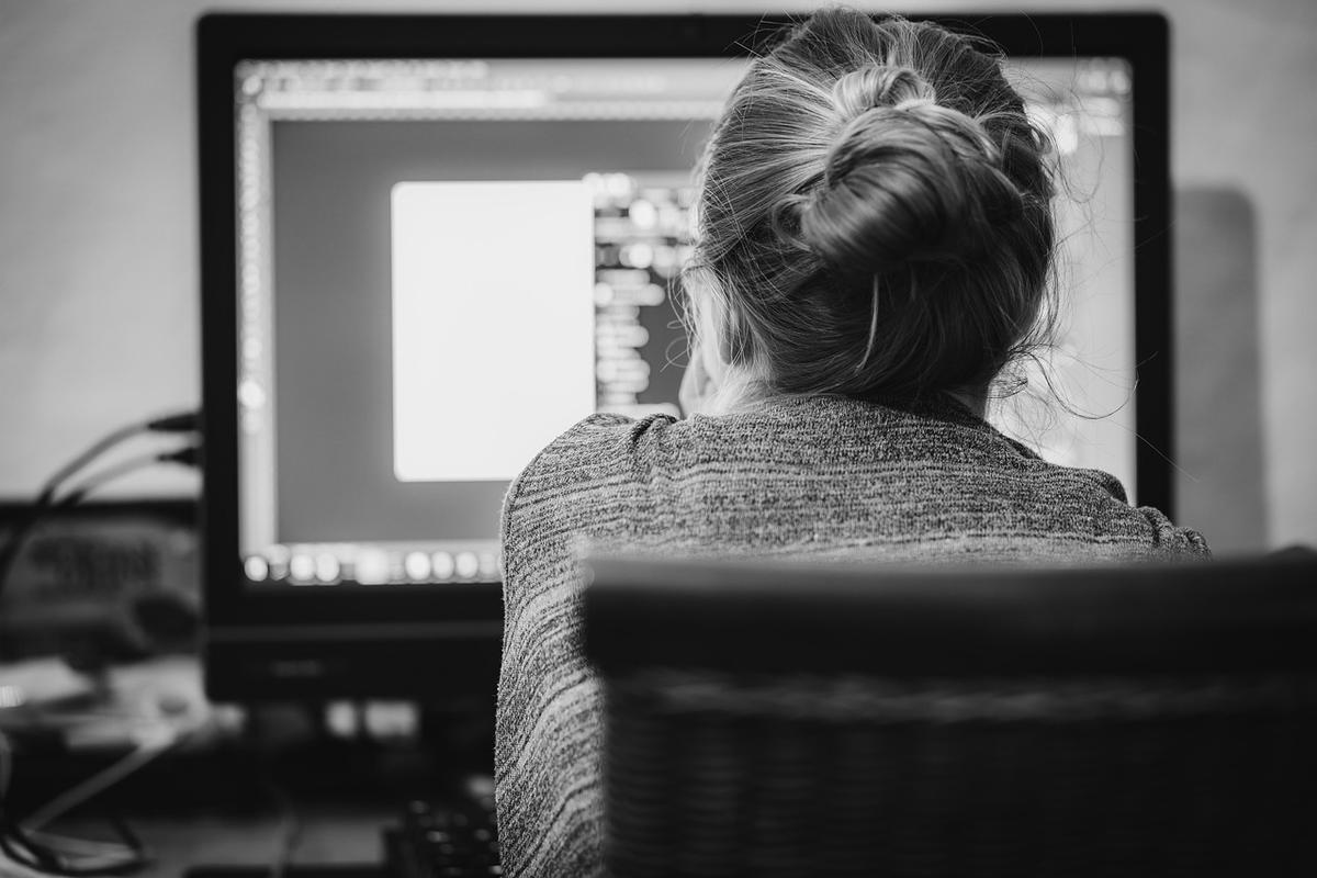 Personne de dos travaillant sur un ordinateur de bureau en noir et blanc Personne de dos travaillant sur un ordinateur de bureau en noir et blanc