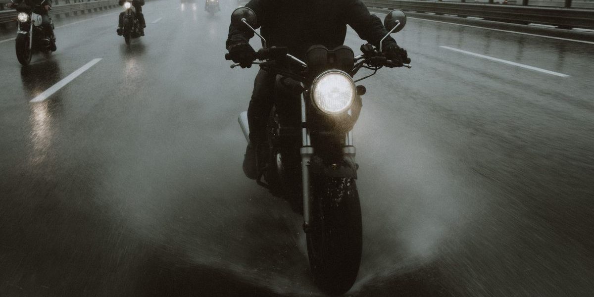 Conducteurs de motos circulant sous la pluie sur une autoroute avec phares allumés
