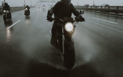 Conducteurs de motos circulant sous la pluie sur une autoroute avec phares allumés